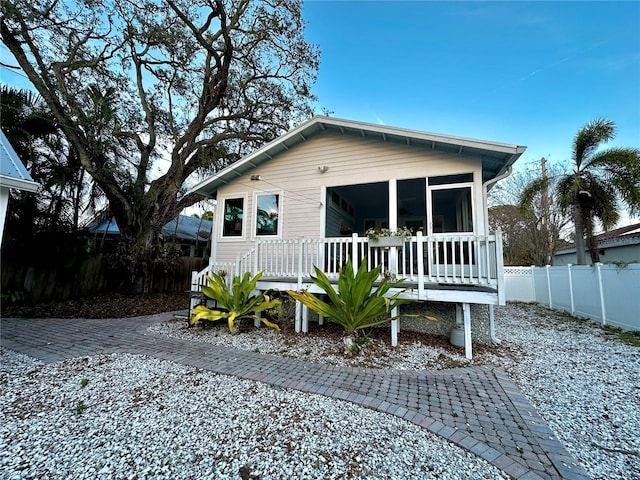 view of front of property featuring a sunroom and fence