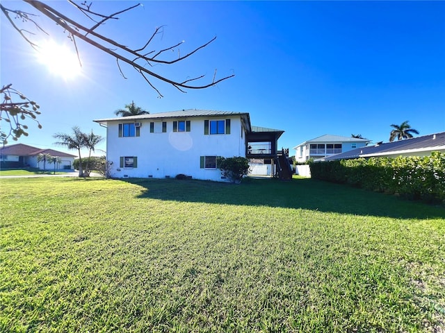 rear view of property featuring crawl space, a yard, and stucco siding