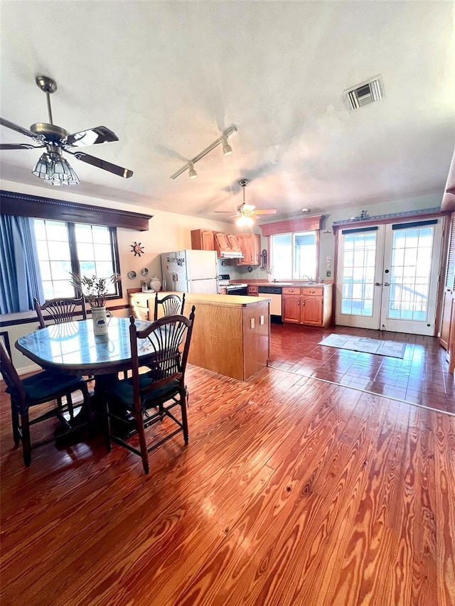 dining room featuring dark wood-style floors, visible vents, ceiling fan, french doors, and a textured ceiling