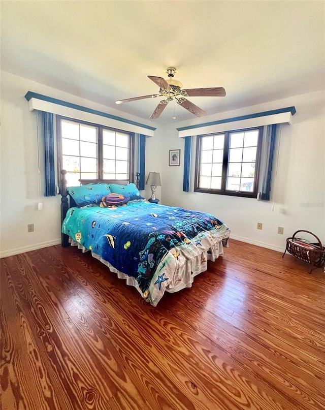 bedroom featuring wood finished floors, baseboards, and ceiling fan