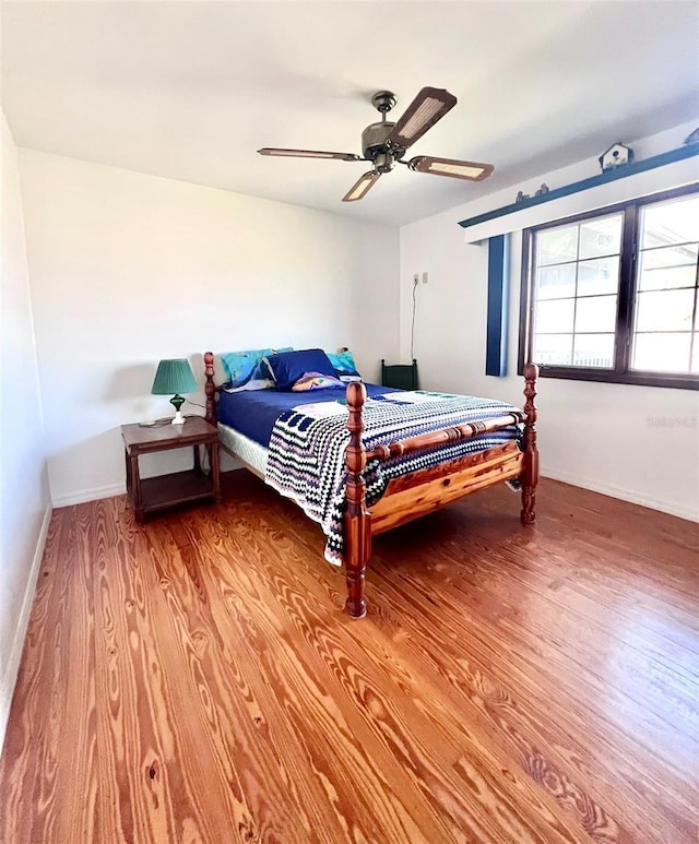 bedroom with light wood-style flooring, a ceiling fan, and baseboards