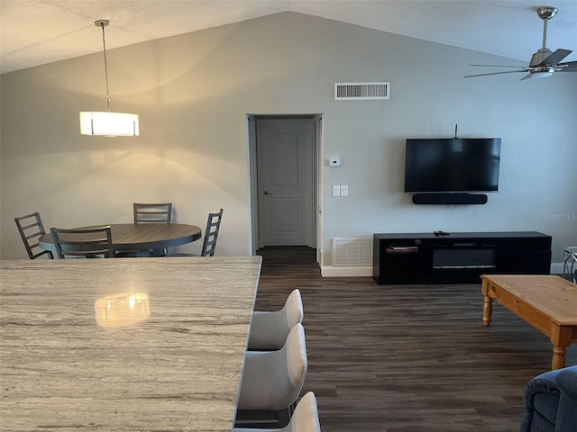 living area with dark wood-style flooring, visible vents, vaulted ceiling, and ceiling fan