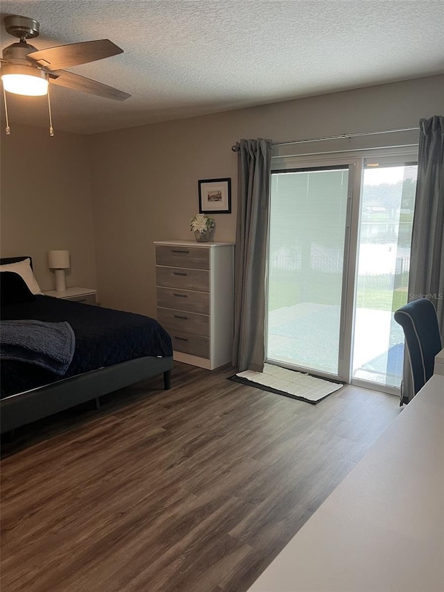 bedroom featuring a textured ceiling, dark wood-style flooring, a ceiling fan, and access to exterior