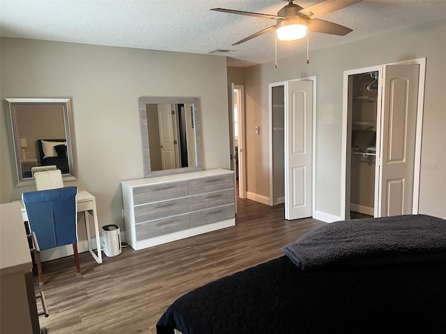 bedroom featuring visible vents, baseboards, a ceiling fan, dark wood-style flooring, and a textured ceiling