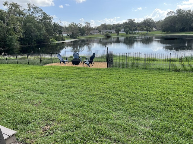 view of yard featuring an outdoor fire pit, a water view, and fence