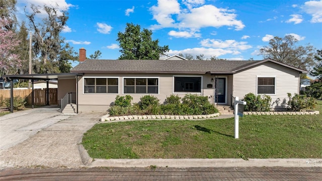 ranch-style house featuring fence, a chimney, concrete driveway, a front yard, and an attached carport