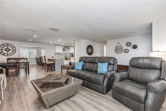 living area with visible vents, recessed lighting, a textured ceiling, and light wood-type flooring