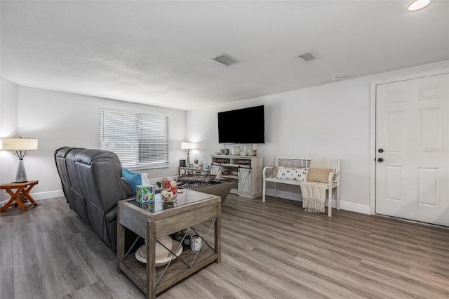 living area featuring baseboards, visible vents, wood finished floors, and a textured ceiling