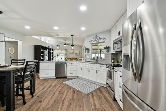 kitchen with stainless steel appliances, light stone countertops, pendant lighting, white cabinetry, and kitchen peninsula