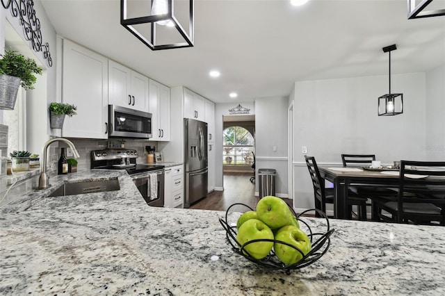 kitchen featuring white cabinetry, stainless steel appliances, sink, light stone counters, and decorative backsplash