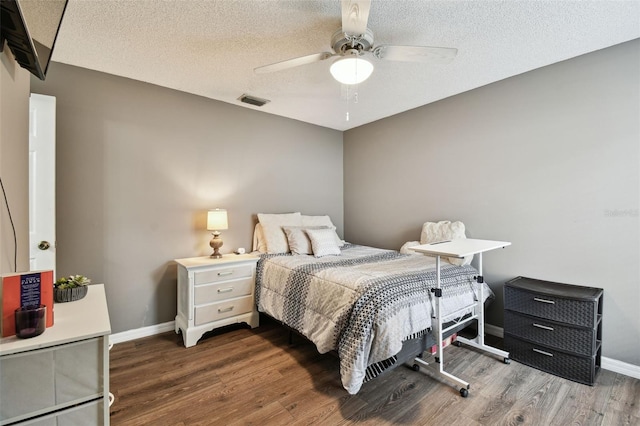 bedroom with dark hardwood / wood-style flooring, ceiling fan, and a textured ceiling