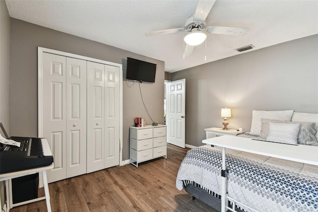 bedroom with a textured ceiling, a closet, ceiling fan, and dark hardwood / wood-style floors