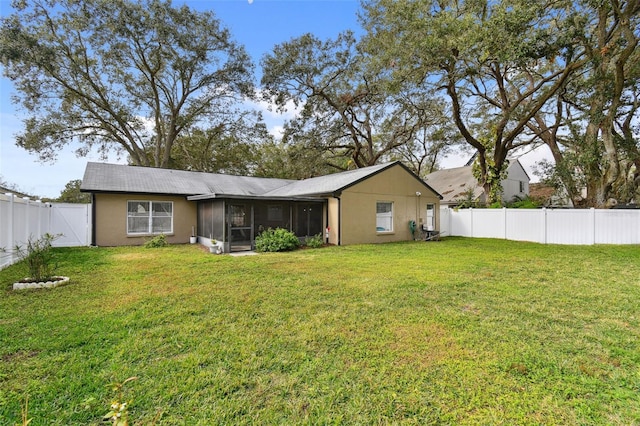 rear view of house with a yard and a sunroom