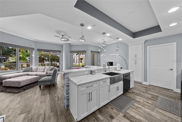 kitchen with open floor plan, wood finished floors, black dishwasher, and a sink