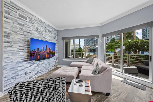 living area featuring ornamental molding, visible vents, baseboards, and wood finished floors