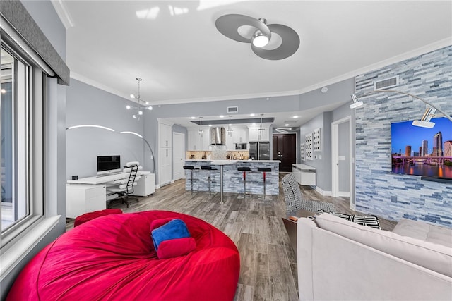 living area with visible vents, crown molding, baseboards, and wood finished floors