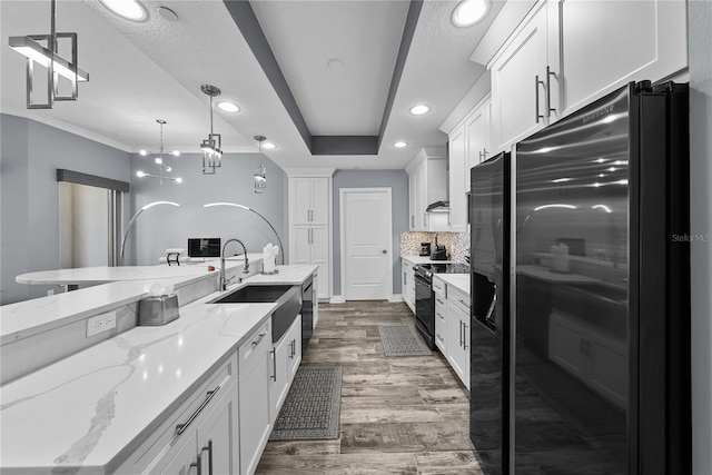 kitchen featuring wood finished floors, black appliances, white cabinetry, pendant lighting, and a sink