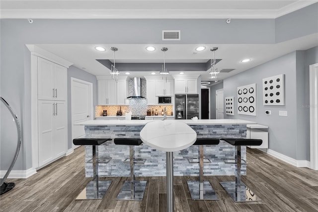 kitchen with visible vents, fridge with ice dispenser, built in microwave, wall chimney exhaust hood, and dark wood finished floors