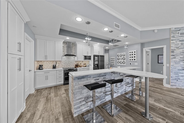 kitchen featuring range with two ovens, visible vents, fridge with ice dispenser, wall chimney range hood, and a raised ceiling