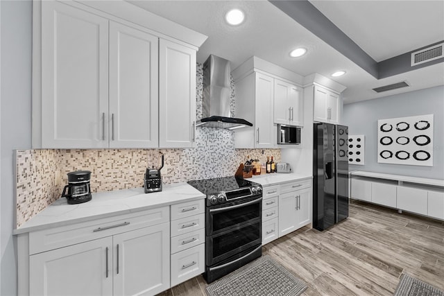 kitchen with stainless steel appliances, white cabinets, visible vents, and wall chimney exhaust hood