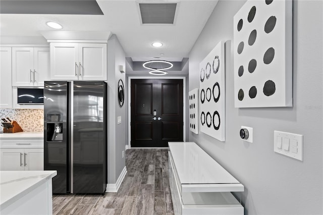 kitchen featuring visible vents, light wood-style floors, white cabinets, fridge with ice dispenser, and backsplash