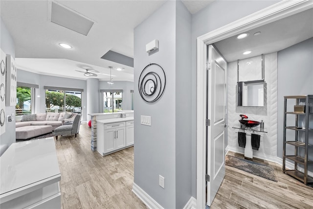 corridor featuring light wood finished floors, recessed lighting, and baseboards