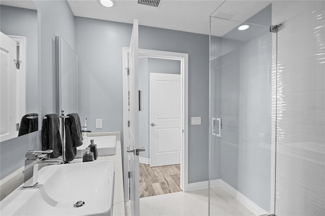 bathroom featuring visible vents, a sink, baseboards, and walk in shower