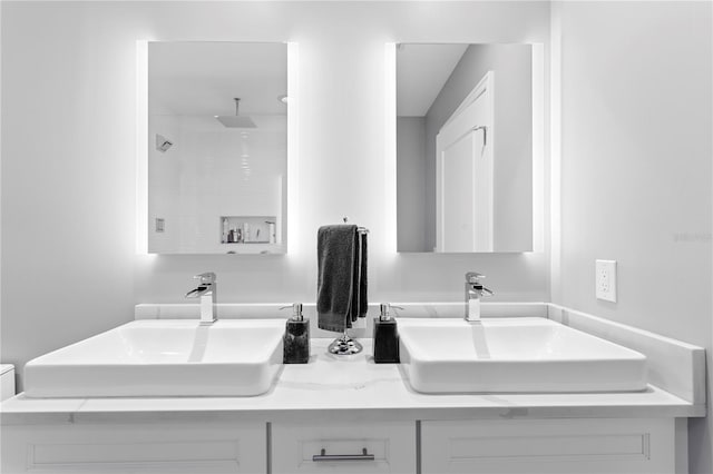 full bathroom featuring double vanity, walk in shower, and a sink