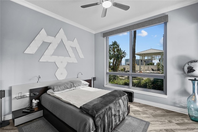 bedroom featuring a ceiling fan, crown molding, baseboards, and wood finished floors