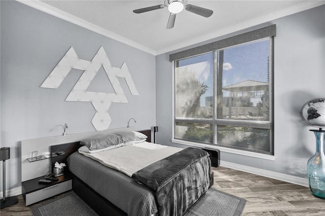 bedroom with ornamental molding, multiple windows, baseboards, and wood finished floors