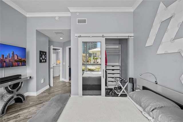 bedroom featuring baseboards, wood finished floors, visible vents, and crown molding