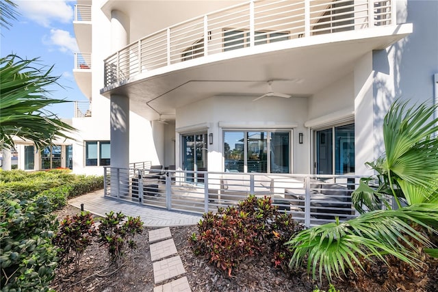 doorway to property featuring a ceiling fan, a balcony, and stucco siding