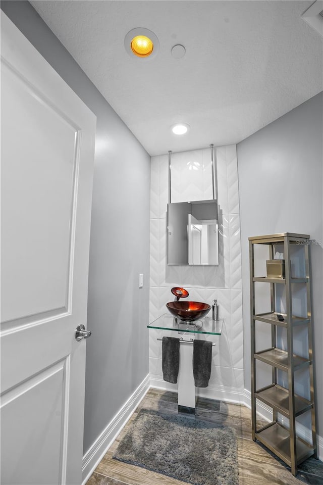 bathroom featuring a sink, baseboards, wood finished floors, and recessed lighting