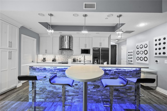 kitchen featuring black microwave, white cabinetry, visible vents, wall chimney range hood, and stainless steel fridge with ice dispenser