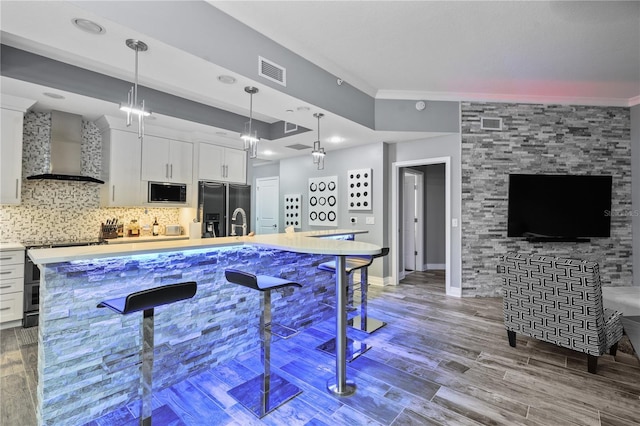 kitchen featuring electric range, visible vents, black fridge, built in microwave, and wall chimney exhaust hood