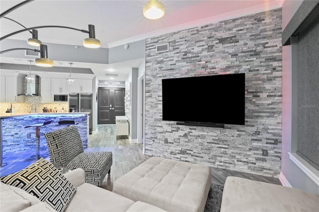 living room featuring light wood-type flooring, baseboards, visible vents, and crown molding