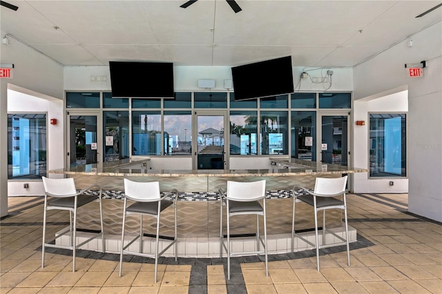 exterior space with stone counters, a ceiling fan, and tile patterned floors