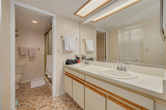 full bathroom with a skylight, a sink, toilet, and double vanity