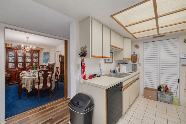 kitchen featuring light tile patterned floors, dishwasher, an inviting chandelier, light countertops, and a sink