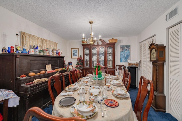 dining space with carpet floors, visible vents, a chandelier, and a textured ceiling