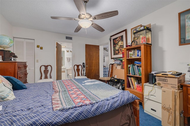 carpeted bedroom featuring a textured ceiling, ensuite bathroom, visible vents, and a ceiling fan