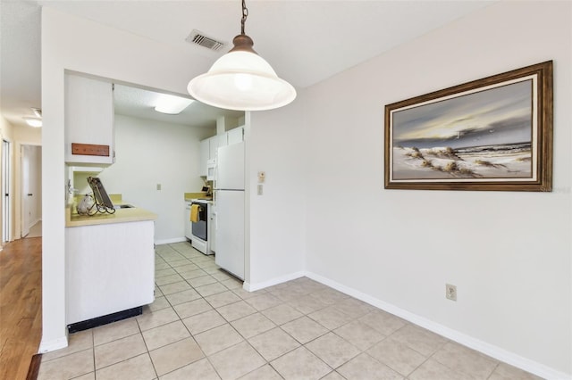 2301 Grenoble Pl Unit 1, Sun City Center, FL 33573 - kitchen featuring baseboards, white appliances, light countertops, white cabinetry, and visible vents