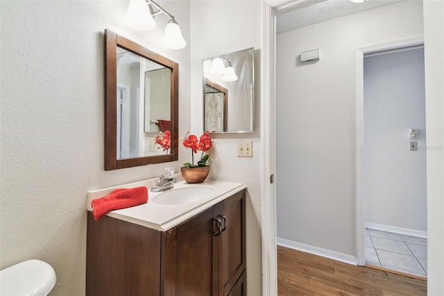 2301 Grenoble Pl Unit 1, Sun City Center, FL 33573 - bathroom with toilet, wood finished floors, vanity, and baseboards