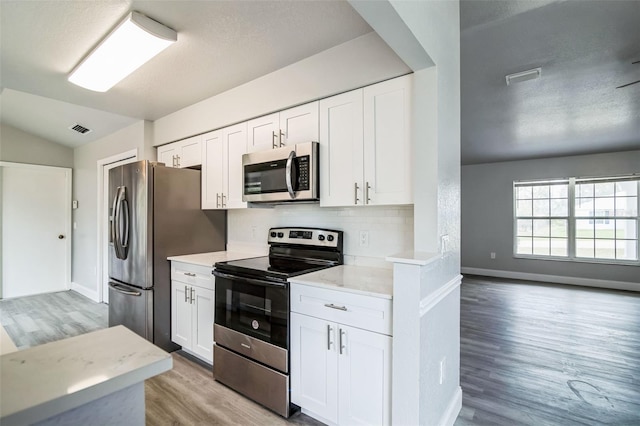 kitchen with stainless steel appliances, light countertops, visible vents, and white cabinetry