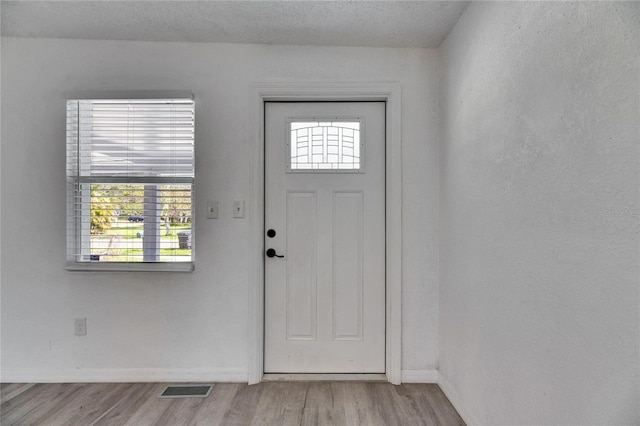 foyer with light hardwood / wood-style floors and a textured ceiling