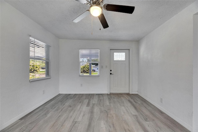 foyer with ceiling fan, light hardwood / wood-style flooring, a textured ceiling, and a wealth of natural light