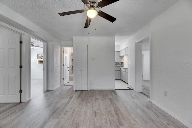 unfurnished living room with light wood-type flooring and a textured ceiling