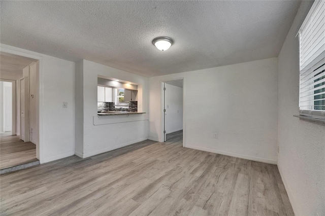 unfurnished room featuring light hardwood / wood-style floors and a textured ceiling