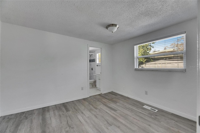 empty room with light hardwood / wood-style flooring and a textured ceiling