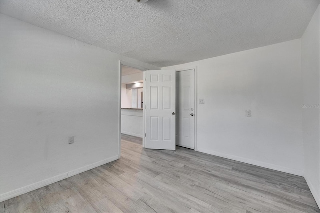 spare room with light wood-type flooring and a textured ceiling